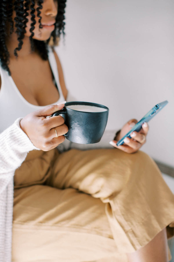 Woman browsing press articles related to Hem Support Wear on her phone with coffee in hand.