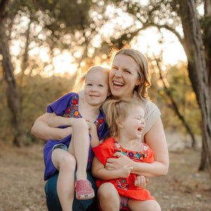 Lauren, Hem's founder with two young girls (her daughters) smiling during sunset